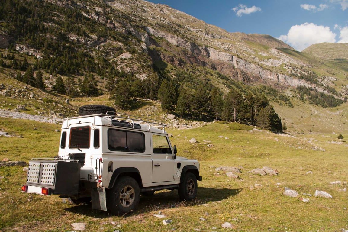 old jeep in field below mountain