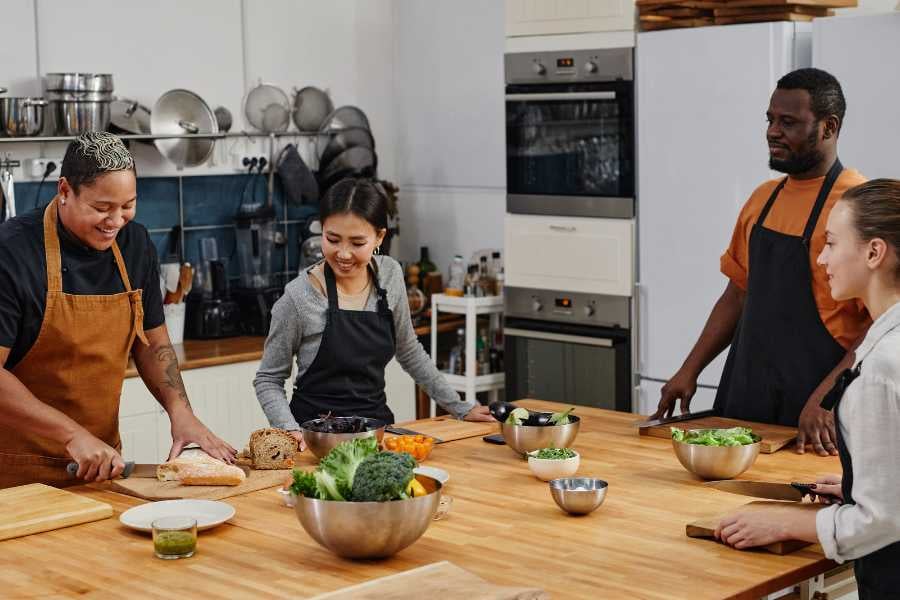  A fun cooking class with people preparing fresh food together in a bright kitchen.