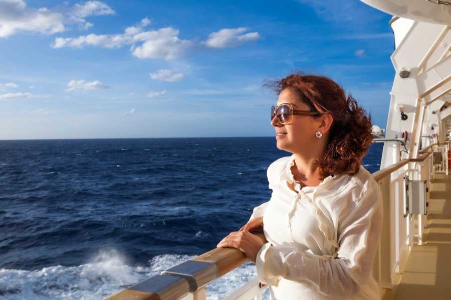 A traveler enjoying the open sea from a cruise ship deck, soaking in the ocean breeze.