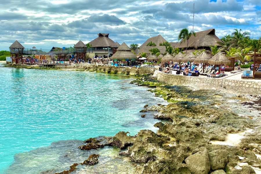 A serene resort nestled along a rocky shoreline with crystal-clear turquoise waters.