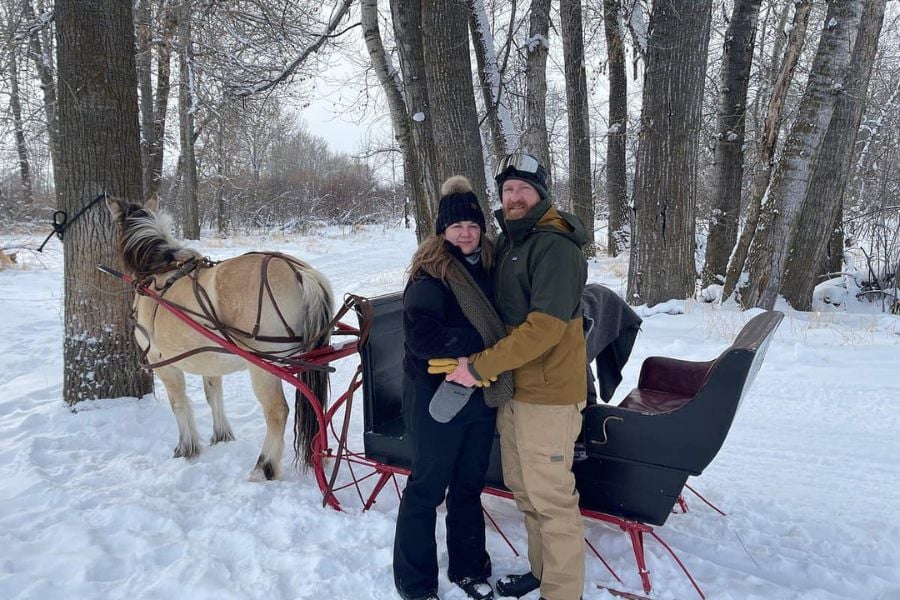 Couple enjoying a snowy horse-drawn sleigh ride.
