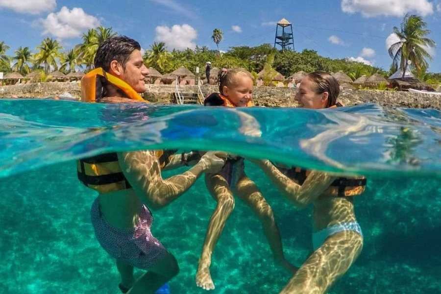 A happy family floats in crystal-clear water, sharing smiles while exploring a tropical snorkeling paradise.