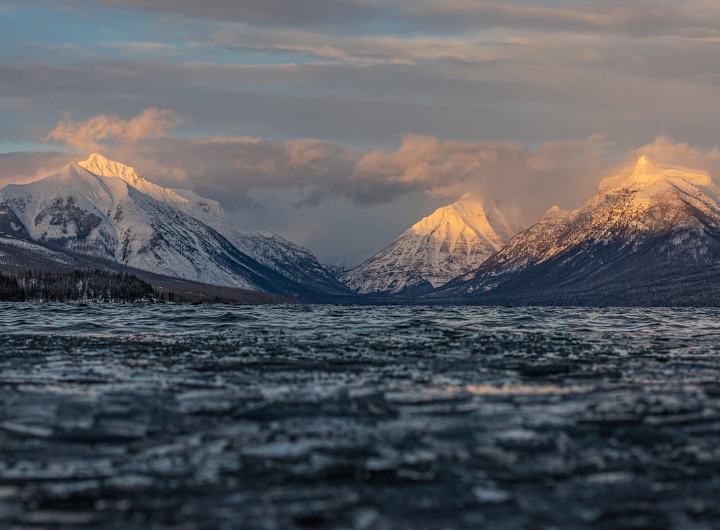 ice floating on lake with sunset mountains behind