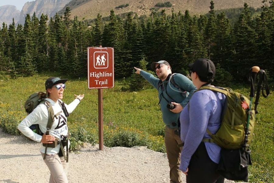 Hikers laugh and point toward the Highline Trail sign.