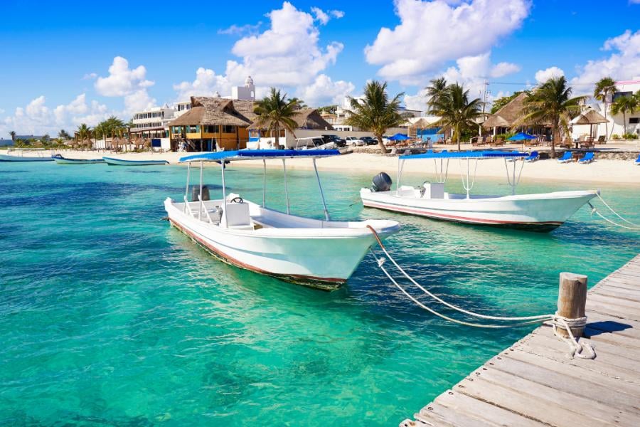 Crystal-clear waters and docked boats invite you to relax on this pristine tropical beach paradise.