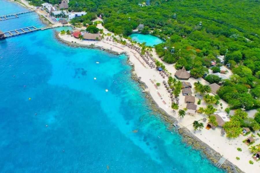 A stunning aerial view of a sandy beach with inviting blue waters, surrounded by tropical greenery.