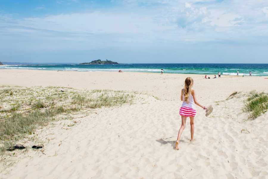 A child joyfully strolling toward the ocean, ready to make memories on a beautiful, sunny beach.