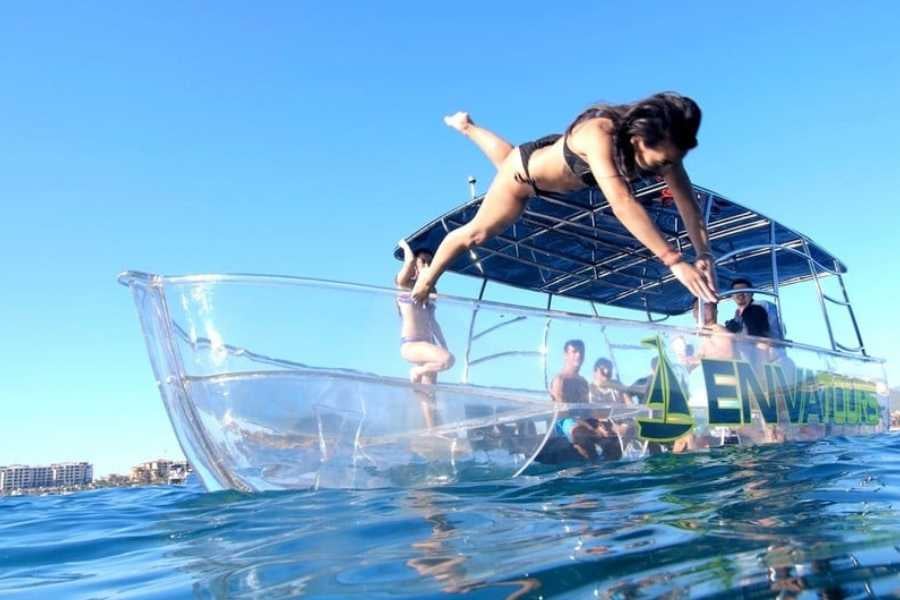 A woman jumps from a transparent boat into the ocean, ready for an exciting snorkeling adventure.