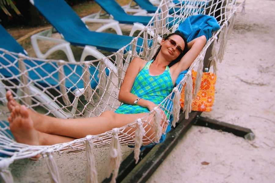 A woman lounging in a hammock, soaking up the sun with a smile and tropical vibes.