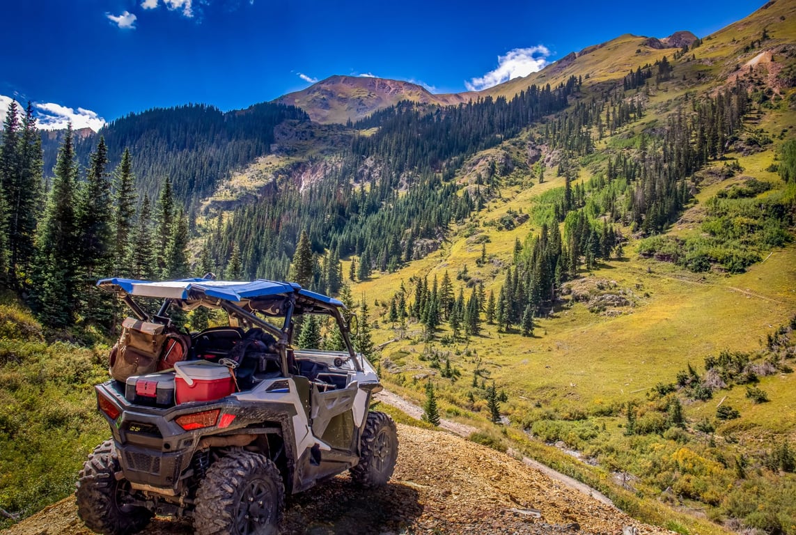 an off-road utv packed for picnic in front of mountain