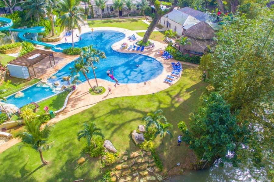 Stunning aerial view of a tropical resort with a sparkling pool, water slide, and lush greenery.