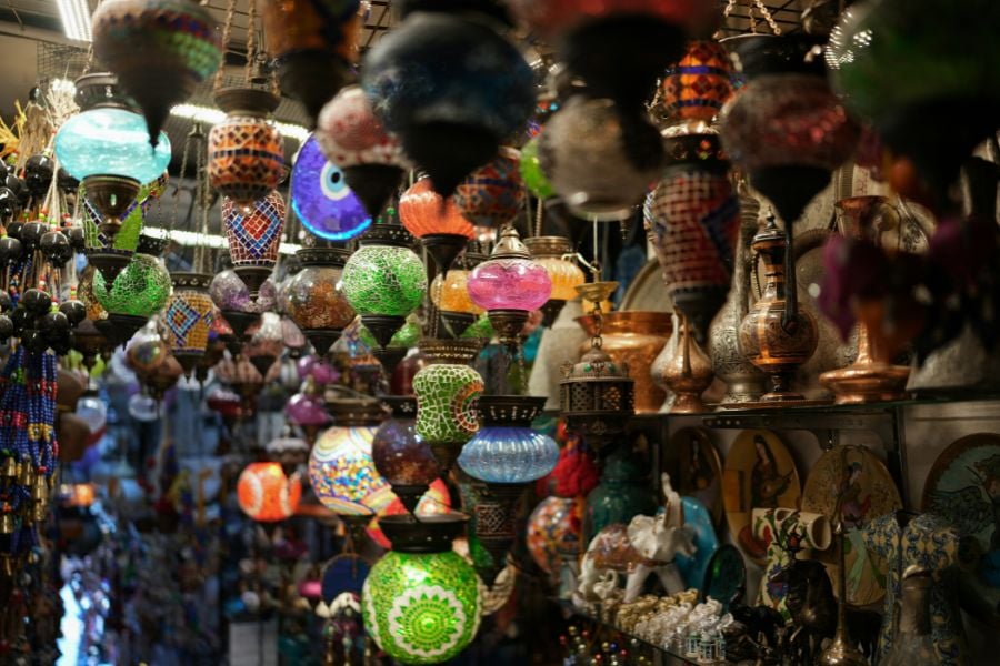 Bright mosaic lamps hang closely together in a busy market.