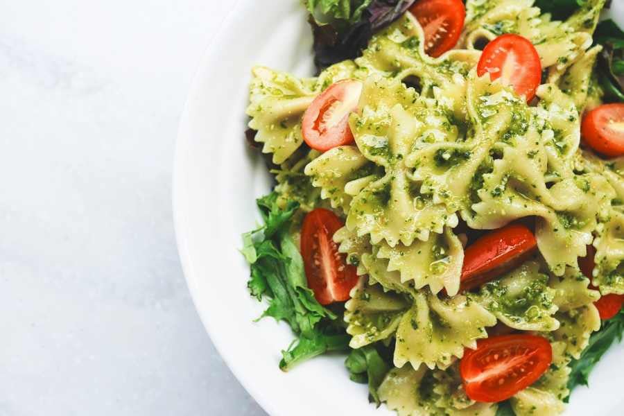 Bowtie pasta with pesto, tomatoes, and greens.