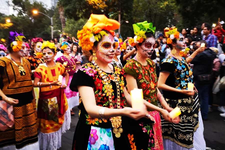 Vibrant Day of the Dead parade with colorful costumes, painted faces, and glowing candles in celebration of heritage.