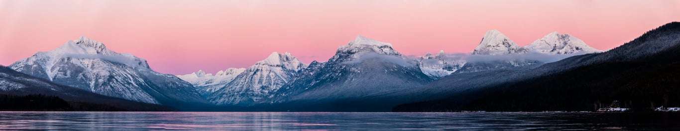 pink sunset with white mountains behind lake