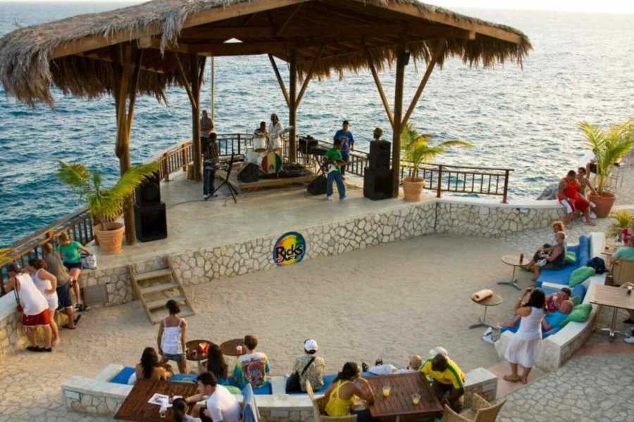 A reggae band performs at a beachfront venue while guests relax and enjoy ocean views.