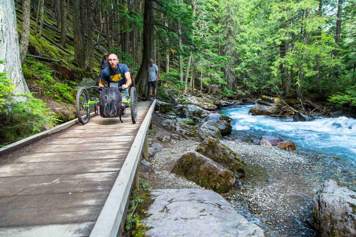 a man drives his off-trail wheelchair on a boardwalk in Glacier Park