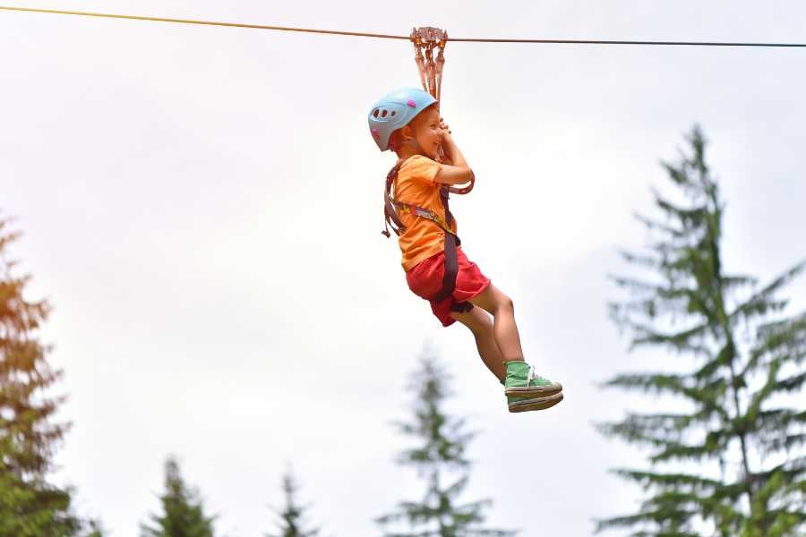 A child excitedly zip-lining through the forest.