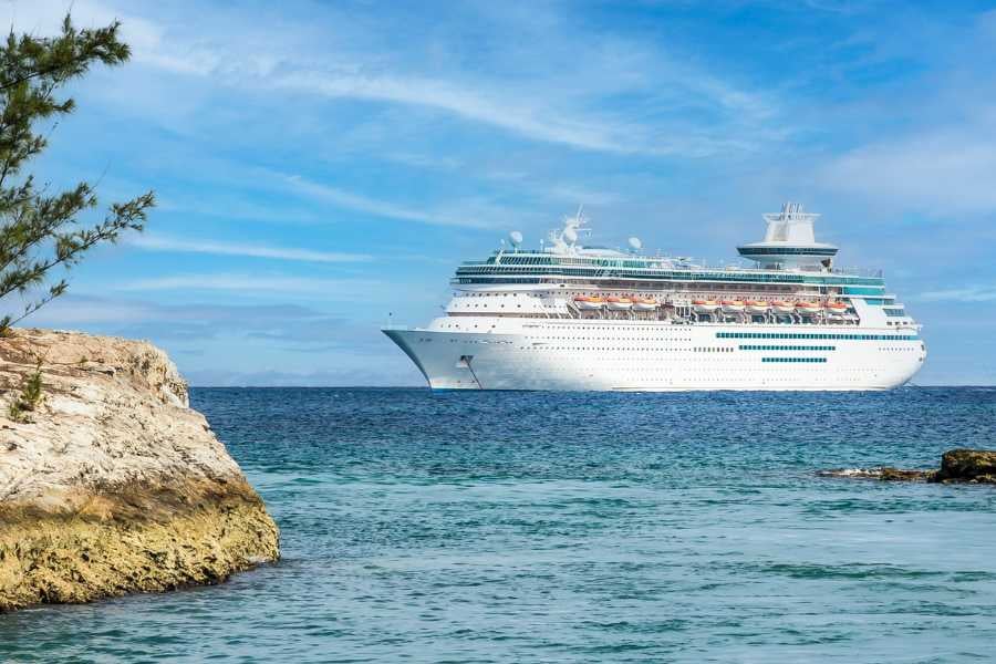  A majestic white cruise ship anchored near rocky shores, set against a backdrop of serene turquoise water.