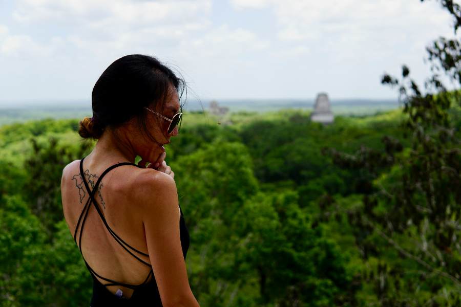 woman looking at mayan ruins in background