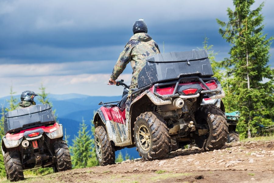 Adventurers climbing rugged mountain trails on ATVs with forest views in Vail, Colorado.