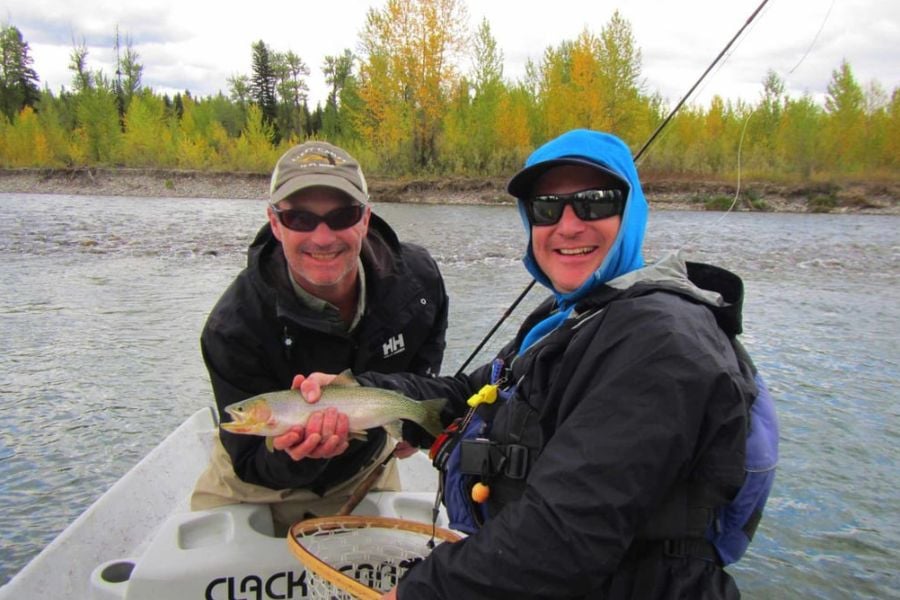 Two smiling fishermen show off their fresh catch.