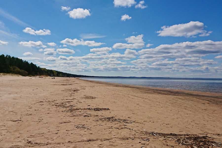  A peaceful, empty beach with soft sand and a sky full of clouds.