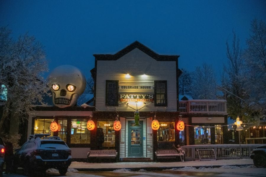 A Halloween-themed restaurant glowing with warm lights on a snowy Breckenridge night.