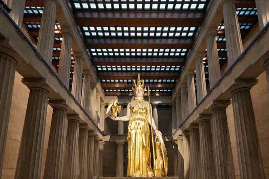 A giant golden statue of Athena stands tall inside a grand temple replica.
