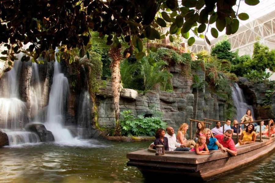 Guests take a relaxing boat ride past waterfalls and tropical plants inside Opryland Hotel & Resort.