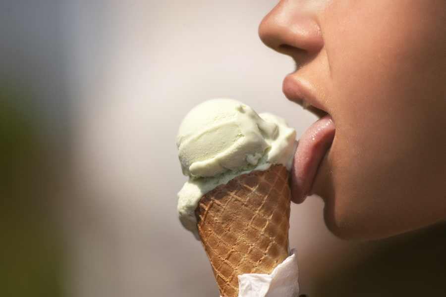 A person enjoys a creamy green ice cream cone.