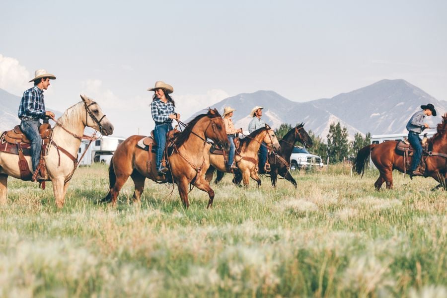 Cowboys ride through Breckenridge&rsquo;s open meadows with the Rocky Mountains behind them.