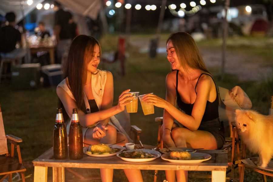 Two girls are sitting at a restaurant on the beach drinking juice