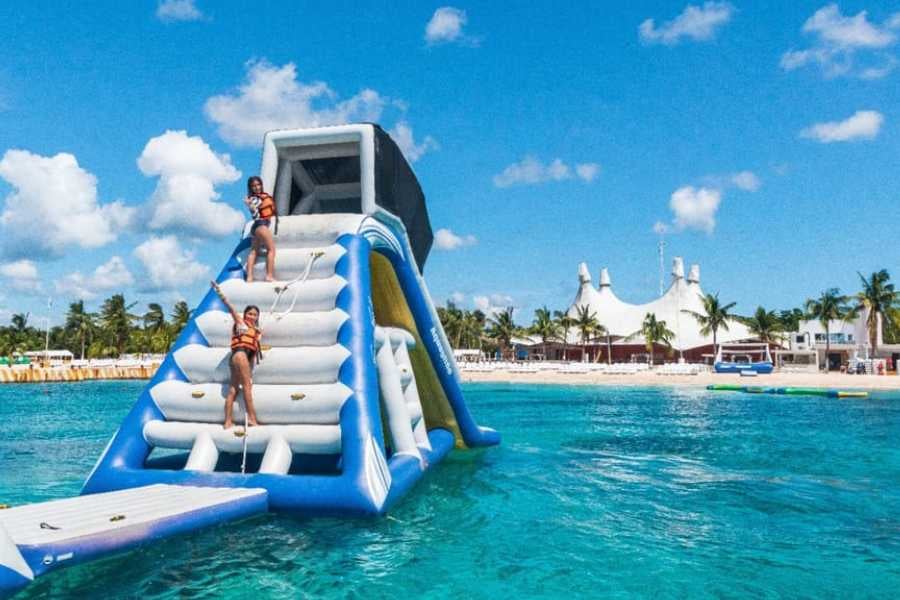 Two thrill-seekers climb an inflatable water slide, ready for an exciting splashdown into the sea.