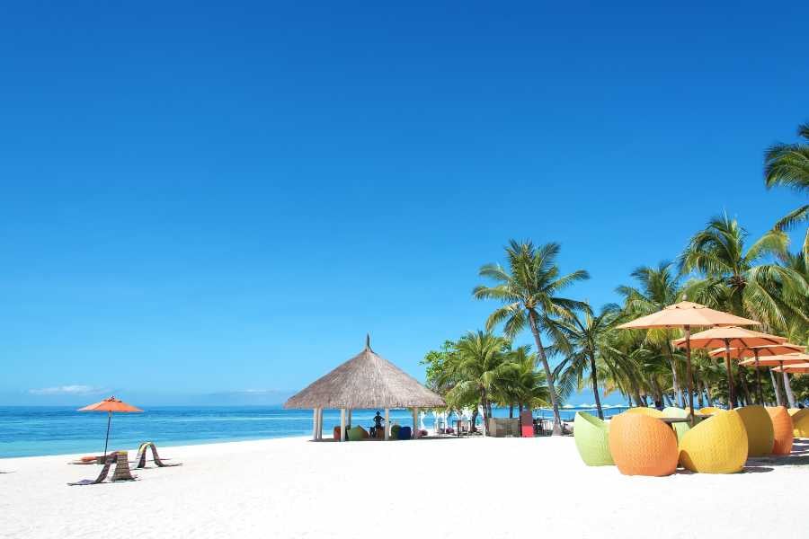 A colorful beachfront lounge area with umbrellas, perfect for enjoying the sun and sea breeze.