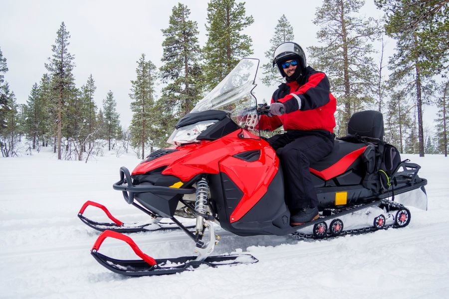 A rider explores a snowy Breckenridge trail on a bright red snowmobile.