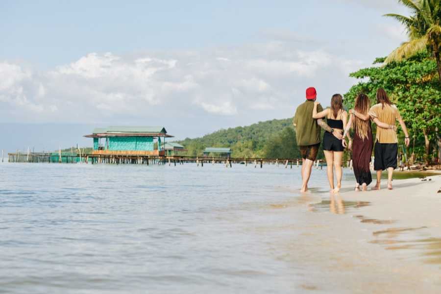 A group of friends walking along a beautiful beach, taking in the scenic views of the ocean.