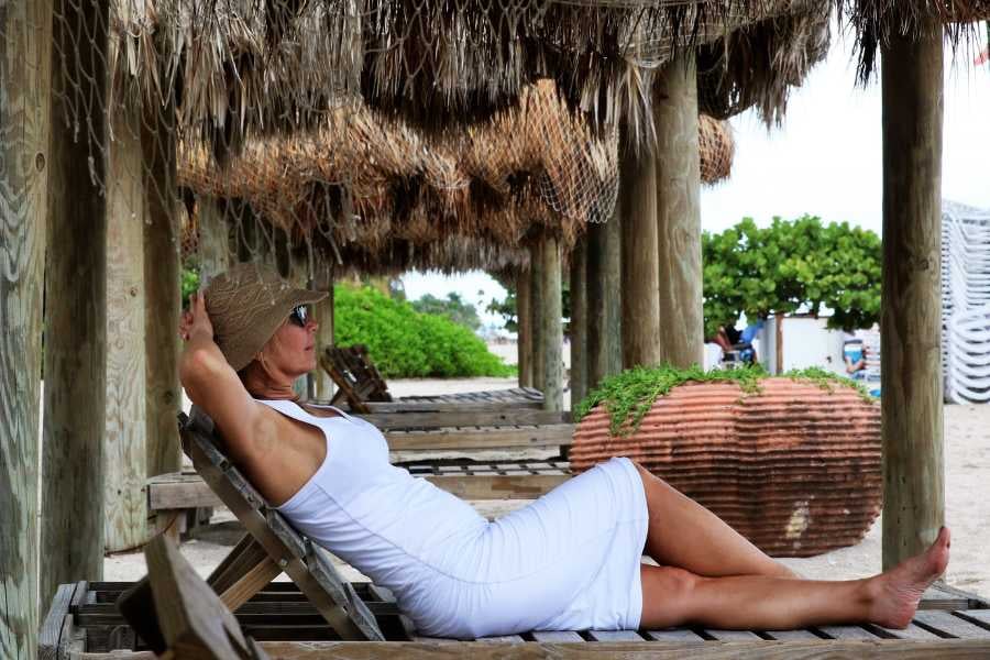 Woman lounging under a rustic wooden canopy on a tranquil beach, soaking in the peaceful vibes.