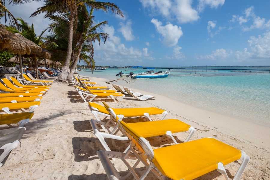 Bright yellow beach chairs lined up on soft white sand, offering front-row seats to crystal-clear turquoise waters.