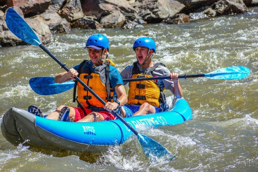 Two friends race through rushing river rapids in a kayak near Breckenridge.