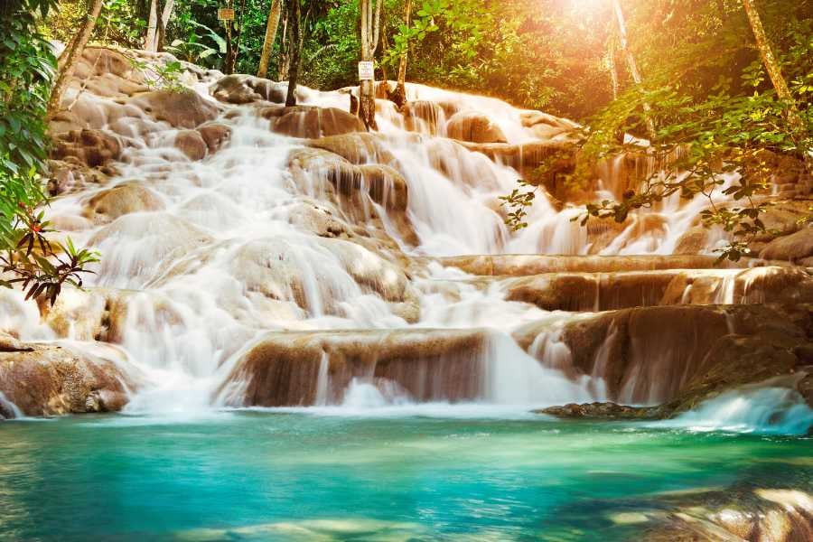 A breathtaking cascade of crystal-clear water flowing over smooth rocks, surrounded by lush green jungle.