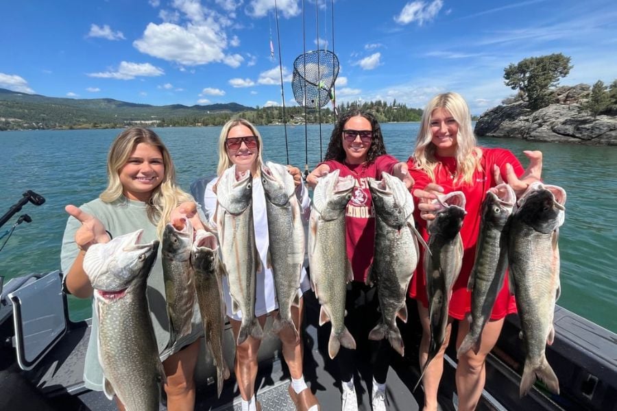 Four friends proudly show off their big catch after a fun day of lake fishing.