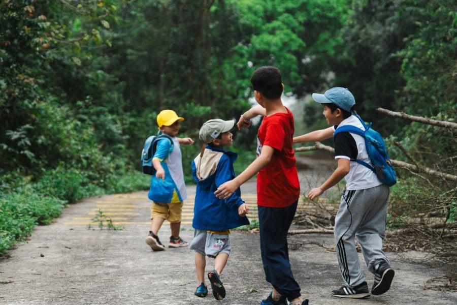Kids play and laugh while hiking on a forest trail.