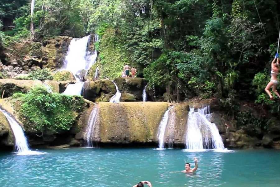 Waterfalls flow into a bright blue pool with rope swings and adventure.