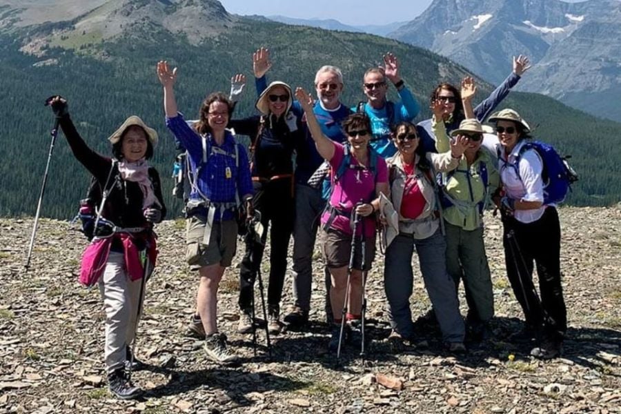 Smiling hikers pose at a mountain summit, celebrating their adventure together.