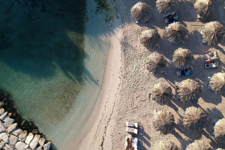 Straw umbrellas line a peaceful Negril beach with crystal-clear water.