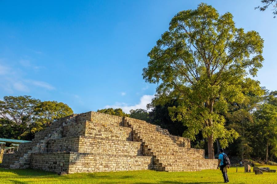 A stunning pyramid stands tall against the blue sky, a perfect backdrop for an adventurous explorer.