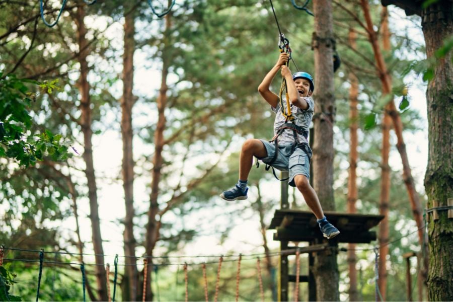 A smiling boy soars through the trees on an exciting zipline adventure.