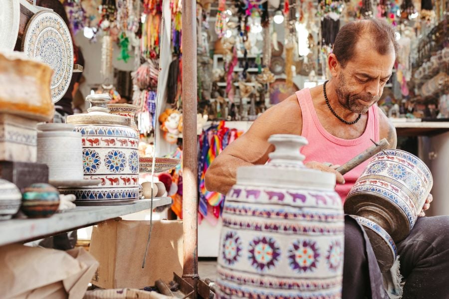 A skilled artisan carefully carves designs into a traditional ceramic pot.