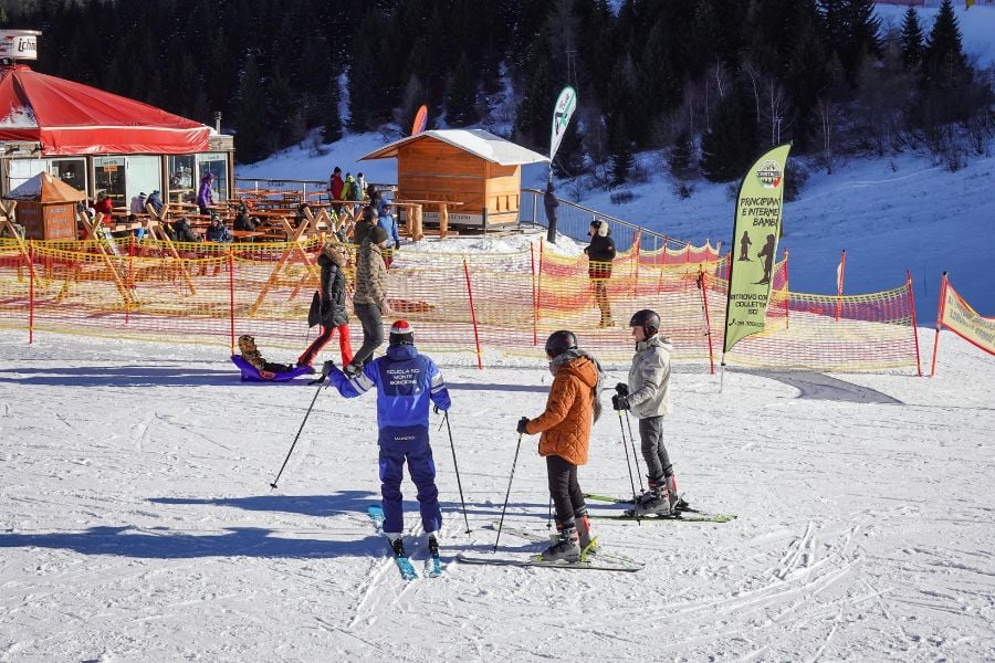 Skiers gather at the beginner area, ready to hit the sunny slopes.